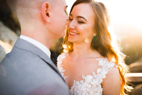 Belle mariée avec un bouquet sur fond de montagne au coucher du soleil — Photo