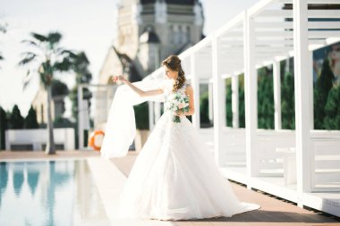 Çekici gelinin portresi, uzun saçlı, büyük buketli poz veren.