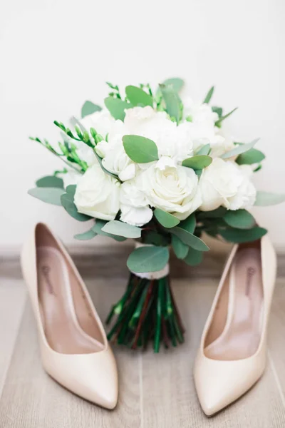 Ζεύγος κομψά και κομψά νυφικά παπούτσια και ένα μπουκέτο τριαντάφυλλα και άλλα λουλούδια — Φωτογραφία Αρχείου