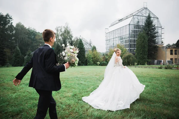 浪漫的婚礼，新娘在公园里从新郎身边跑开 — 图库照片