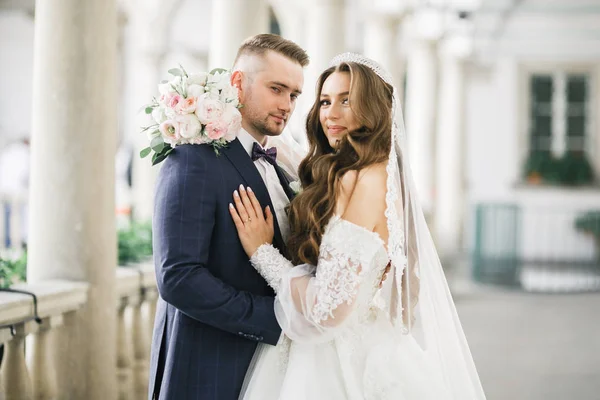 Beau jeune couple de mariage posant avec bouquet de fleurs dans les mains — Photo