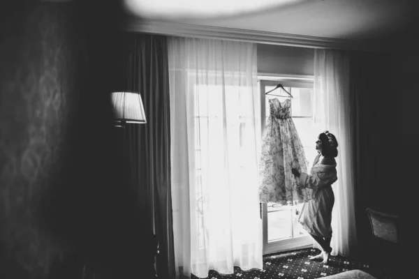 Linda noiva em roupão posando e se preparando para o rosto cerimônia de casamento em uma sala — Fotografia de Stock