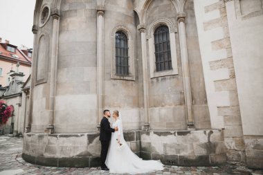 Muhteşem mutlu çift birbirine yakın duruyor ve eski şehir geçmişine, düğün fotoğrafına, Avrupa şehrine, Lviv 'de düğün gününe bakıyor.