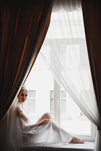 Hermosa novia con vestido de novia de moda con plumas con maquillaje de lujo deleite y peinado, estudio sesión de fotos interior — Foto de Stock