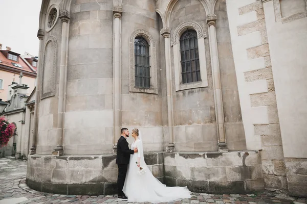 Superbe couple heureux debout près l'un de l'autre et regardant dans les yeux le fond de la vieille ville, photo de mariage, ville européenne, jour du mariage à Lviv — Photo