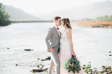 Düğün çifti, damat ve gelin kucaklaşıyor, nehir kenarında.