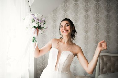 Cüppeli muhteşem gelin bir odada düğün töreni için poz veriyor ve hazırlanıyor.