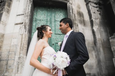 Muhteşem mutlu çift birbirine yakın duruyor ve eski şehir geçmişine, düğün fotoğrafına, Avrupa şehrine, Lviv 'de düğün gününe bakıyor.