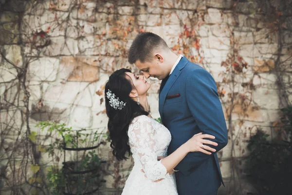 Ravissant couple de mariage heureux, mariée avec longue robe blanche posant dans la belle ville — Photo