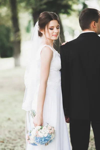 Casal elegante de recém-casados felizes andando no parque em seu dia de casamento com buquê — Fotografia de Stock