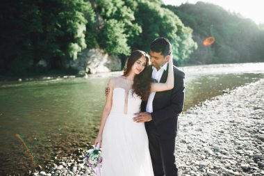 Doğadaki düğün çifti birbirine sarılıyor. Beyaz elbiseli güzel bir kız. Takım elbiseli adam