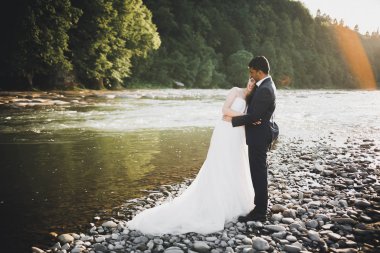 Düğün çifti, damat ve gelin kucaklaşıyor, nehir kenarında.