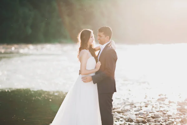 Hochzeitspaar, Bräutigam und Braut umarmen sich, im Freien am Fluss — Stockfoto