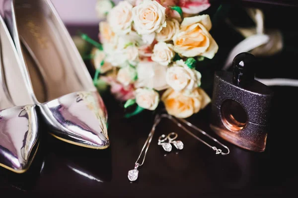 Chaussures de mariée et bijoux fantaisie avec un bouquet de roses et autres fleurs . — Photo