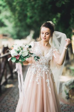 Çekici gelinin portresi, uzun saçlı, büyük buketli poz veren.