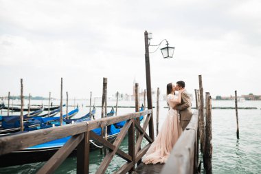 Romantik, peri masalı, mutlu yeni evli çift parkta sarılıp öpüşüyor, arka planda ağaçlar...