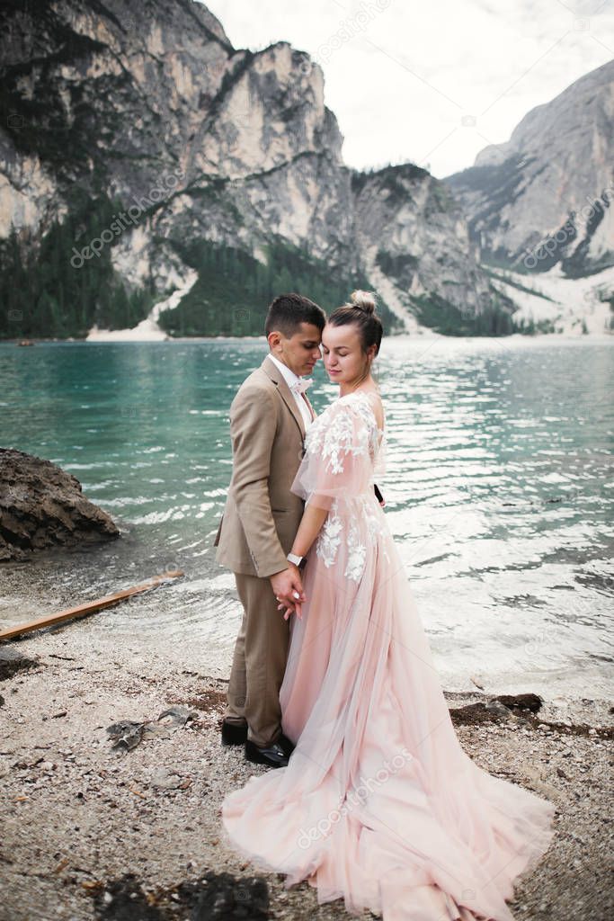 Young couple near lake Karersee, Italy. Holding hands at the stone at lake