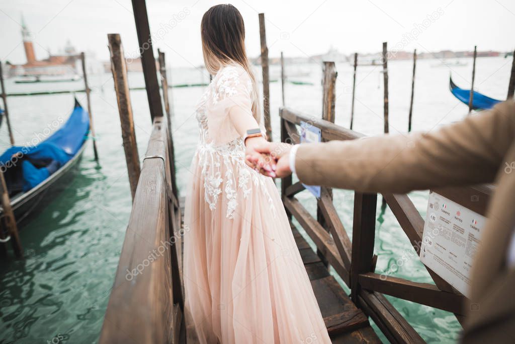 Wedding couple staying on a bridge near the canal with gondolas in Venice, Italy. Follow me