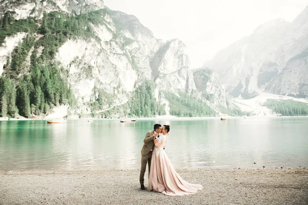 Joven pareja cerca de un hermoso lago en las montañas. Los amantes de la música se aman unos a otros y sonríen — Foto de Stock