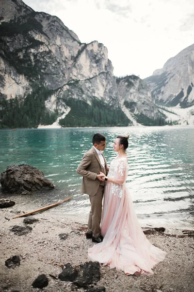 Pareja joven cerca del lago Karersee, Italia. Tomando de la mano en la piedra en el lago —  Fotos de Stock