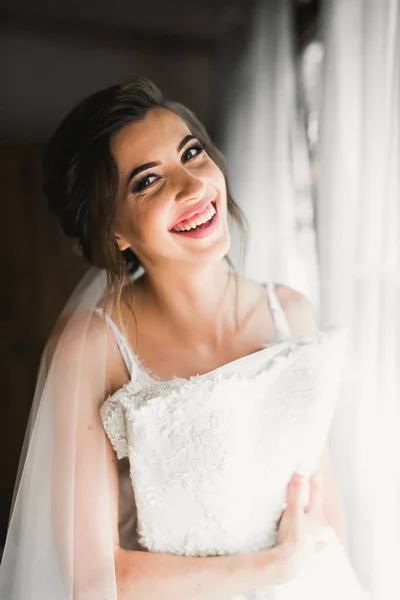 Preciosa novia en bata posando y preparándose para la ceremonia de boda cara en una habitación — Foto de Stock