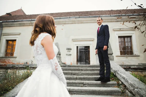 Piękna para weselna wspina się po przepięknych schodach trzymając się za ręce i patrząc na siebie — Zdjęcie stockowe