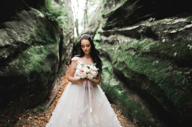 Gelin çiçekli büyük ve güzel bir düğün buketi tutuyor.