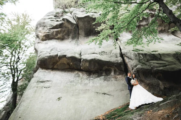 Hermosa novia hermosa posando para el novio y divertirse cerca de las montañas con una vista increíble, espacio para el texto, pareja de boda —  Fotos de Stock