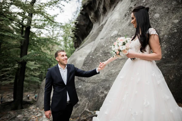Όμορφη πανέμορφη νύφη που ποζάρει στον γαμπρό και διασκεδάζει κοντά στα βουνά με καταπληκτική θέα, χώρος για κείμενο, ζευγάρι γάμου — Φωτογραφία Αρχείου