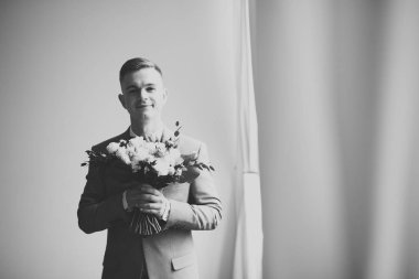 Yaka çiçeğiyle poz veren mutlu yakışıklı damat.