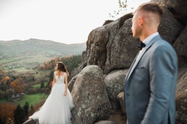 Dağların arka planında sevgi dolu bir koca ve kadın. Sevgili çift duygusal olarak vakit geçirir.