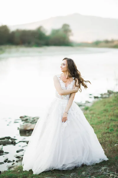 Ritratto di splendida sposa con lunghi capelli in piedi vicino al fiume — Foto Stock