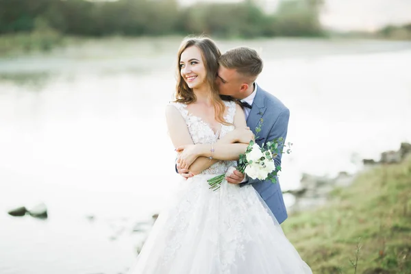 Bröllop par, brudgum och brud kramas, utomhus nära floden — Stockfoto