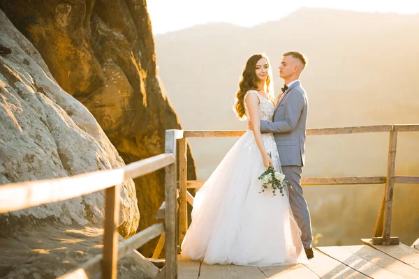 Couple de mariage sur la nature se serre dans ses bras. Belle fille modèle en robe blanche. Homme en costume — Photo