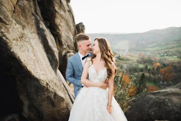 Šťastný svatební pár pózující nad krásnou krajinou v horách — Stock fotografie