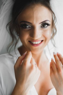 Cüppeli muhteşem gelin bir odada düğün töreni için poz veriyor ve hazırlanıyor.