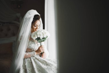 Lüks bir gelin, bir kız buketle poz veriyor ve gülümsüyor.