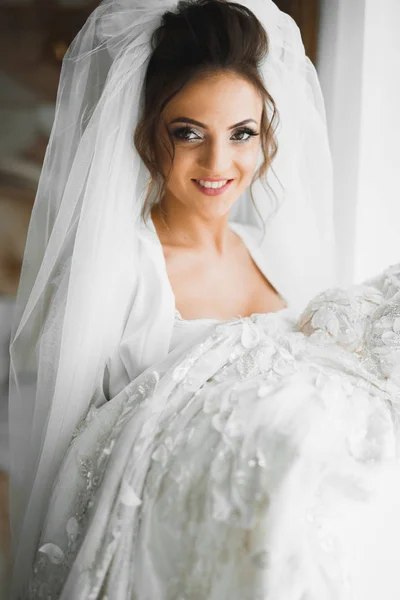 Hermosa novia con vestido de novia de moda con plumas con maquillaje de lujo deleite y peinado, estudio sesión de fotos interior —  Fotos de Stock