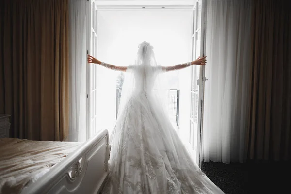 Hermosa novia con vestido de novia de moda con plumas con maquillaje de lujo deleite y peinado, estudio sesión de fotos interior — Foto de Stock