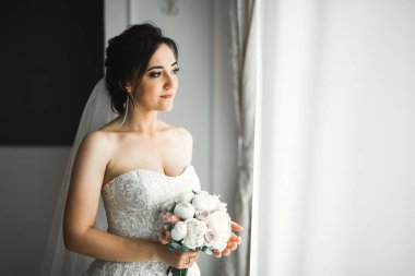 Gelin çiçekli büyük ve güzel bir düğün buketi tutuyor.