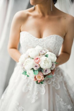 Gelin çiçekli büyük ve güzel bir düğün buketi tutuyor.