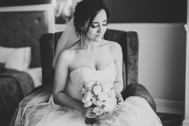 Lüks bir gelin, bir kız buketle poz veriyor ve gülümsüyor.