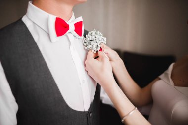 Gelin, damat ceketine yeşil yapraklı beyaz yaka çiçeğini iğneledi.