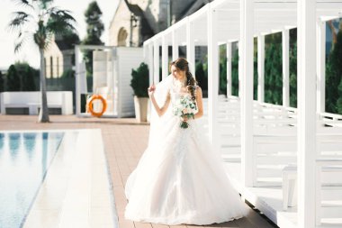 Parkta poz veren zarif beyaz elbiseli güzel gelin.