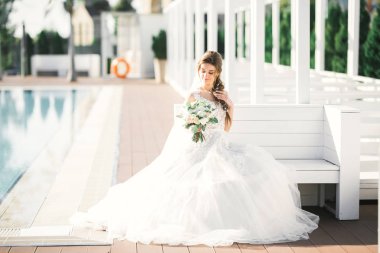 Parkta poz veren zarif beyaz elbiseli güzel gelin.