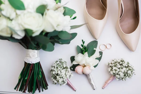 Een paar elegante en stijlvolle bruidsschoenen met trouwringen en een boeket rozen en andere bloemen — Stockfoto