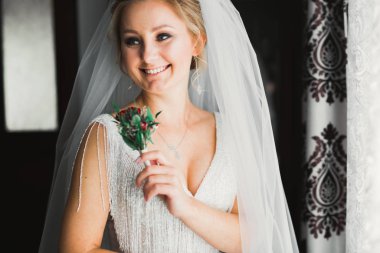 Çekici gelinin portresi, uzun saçlı, büyük buketli poz veren.