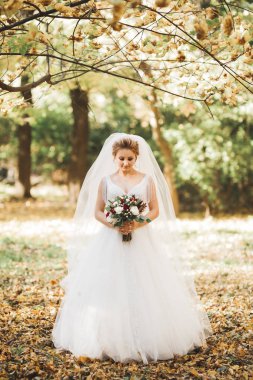 Gelin çiçekli büyük ve güzel bir düğün buketi tutuyor.