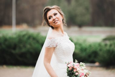 Çekici gelinin portresi, uzun saçlı, büyük buketli poz veren.