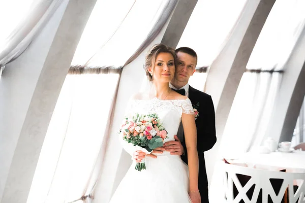 Beau jeune couple de mariage posant avec bouquet de fleurs dans les mains — Photo